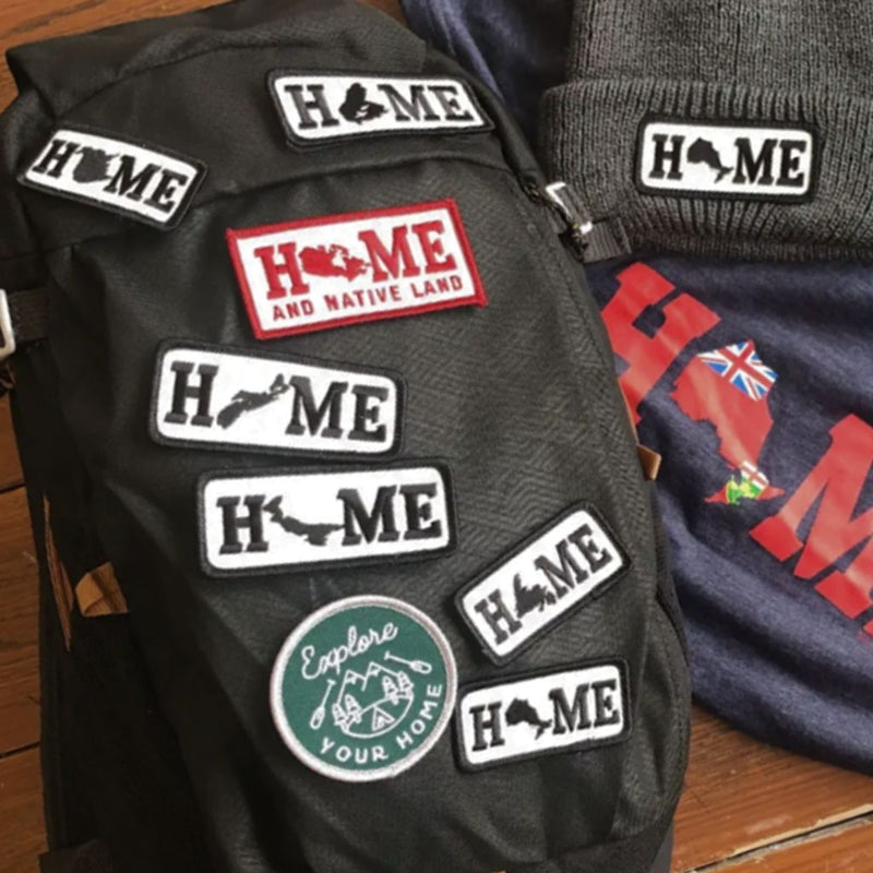 backpack with patches attached, grey toque with patch and t-shirt laying on a wood floor