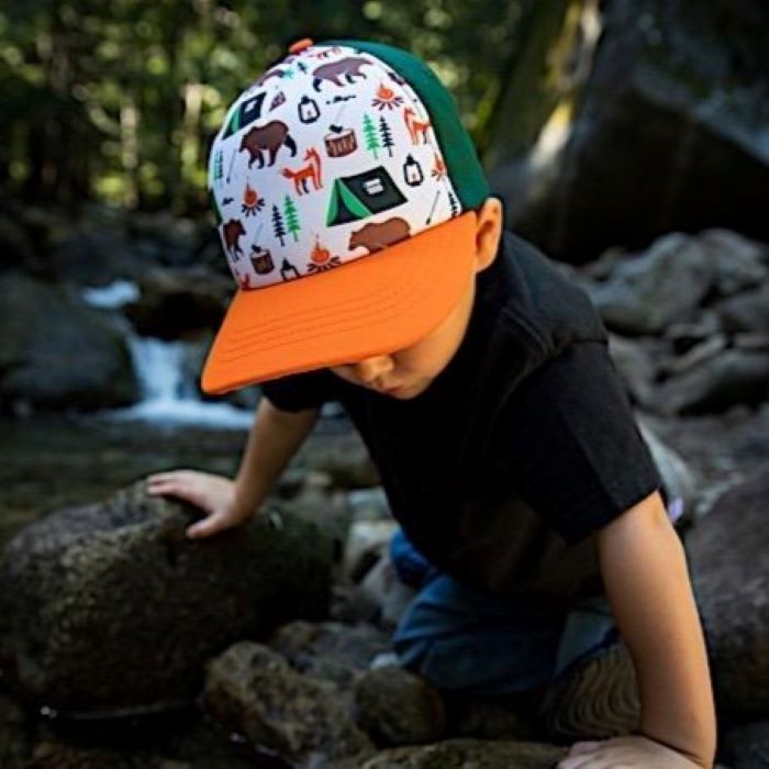 kid climbing some rocks with a camping themed hat on