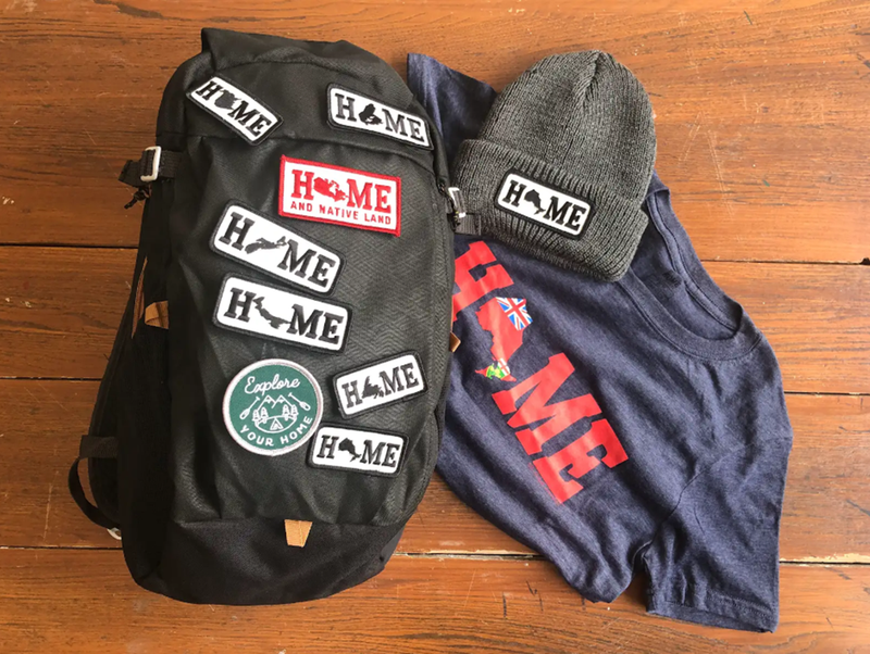 backpack with patches attached, grey toque with patch and t-shirt laying on a wood floor