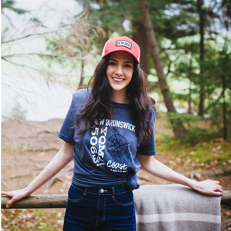 Person leaning on wood fence with a My HOME Apparel t-shirt on & red cap