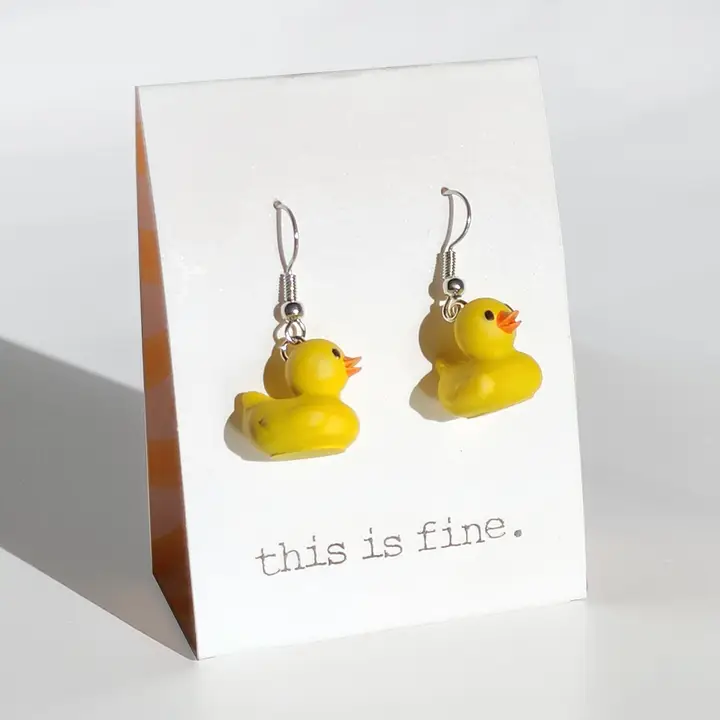 Yellow rubber duck earrings on a card with 'this is fine' text.