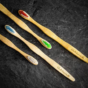 All four adult tooth brushes laying on black stone tile