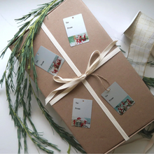 Load image into Gallery viewer, gift wrapped in brown paper with bow and four gift tags on top
