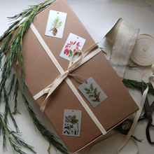 Load image into Gallery viewer, gift wrapped in brown paper with bow and four gift tags on top
