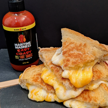 Load image into Gallery viewer, grilled cheese piled high oozing with cheese and a bottle labelled Hot Sauce in orange
