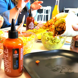 close up of table filled with condiments, a wrap with a bottled  with Hot Sauce written in white