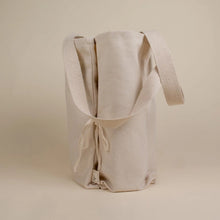 Load image into Gallery viewer, cream coloured bag side view with tie and handles are hanging down
