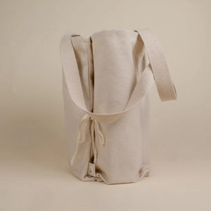 cream coloured bag side view with tie and handles are hanging down