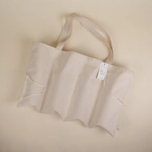 Load image into Gallery viewer, cream coloured bag laying on it&#39;s side with straps and tag
