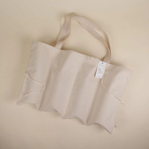 cream coloured bag laying on it's side with straps and tag