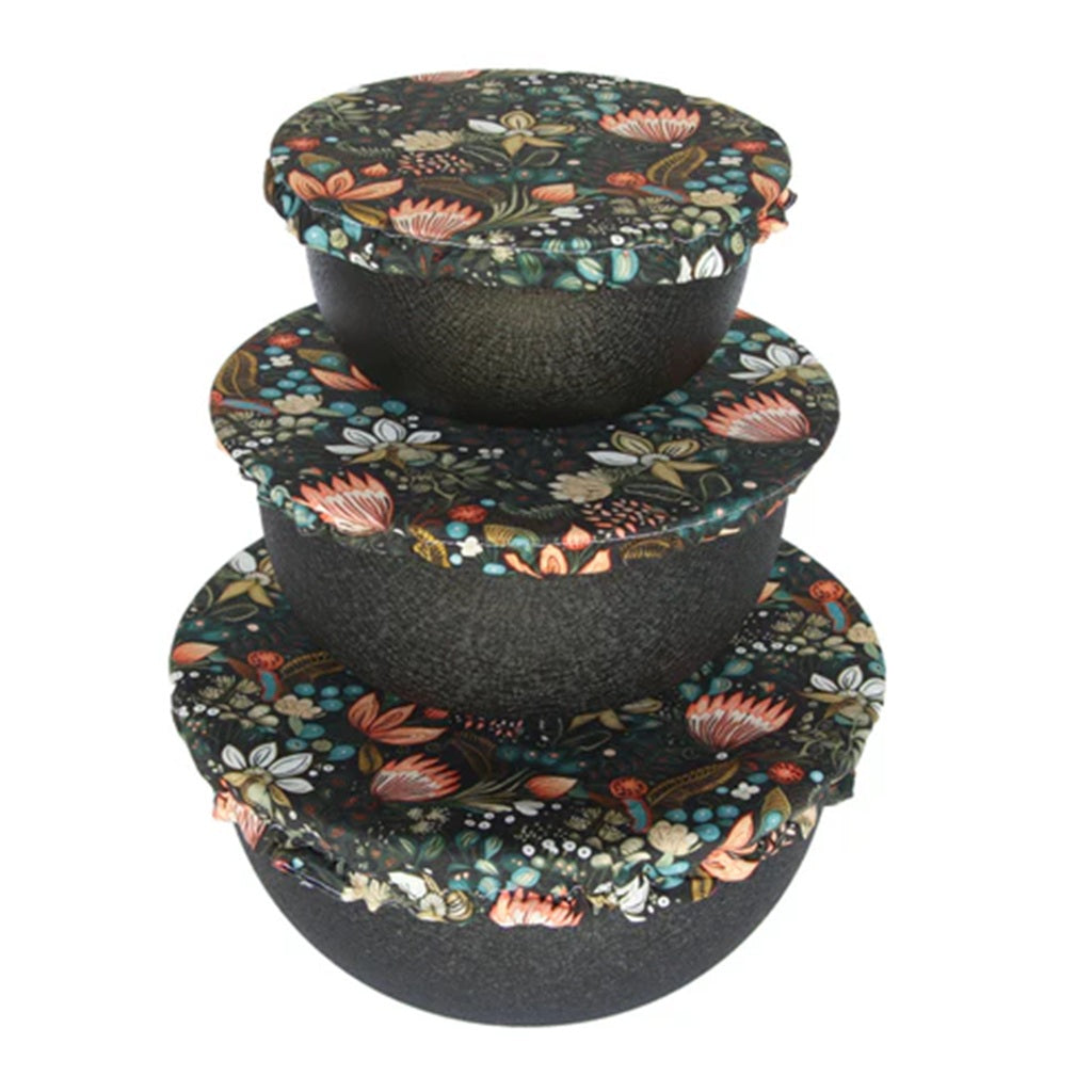 Set of three black stacked bowls with floral bowl covers on a white background