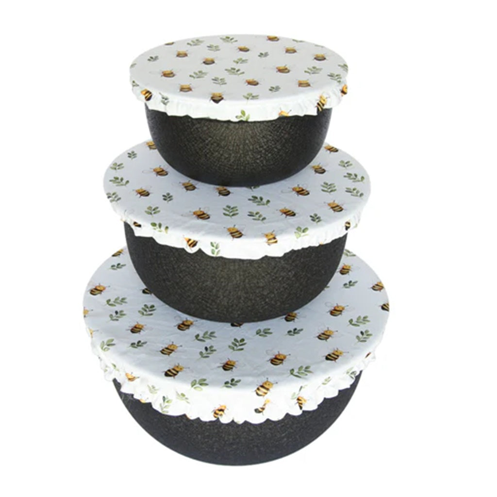 Three black bowls with cotton covers featuring bee patterns on a white background