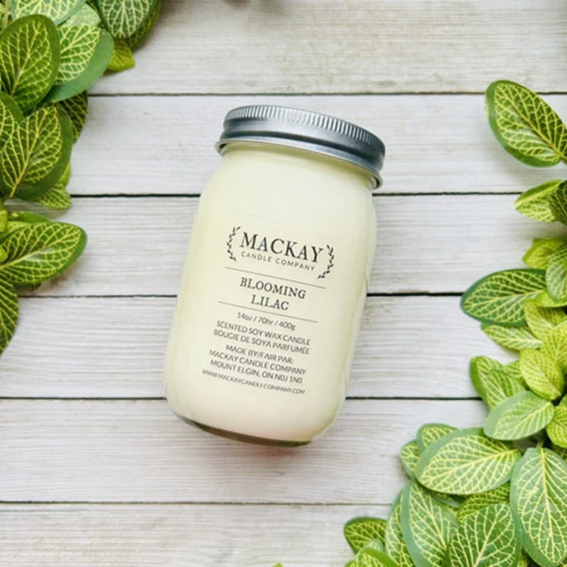 Mackay Candle Company jar on a wooden surface with green leaves