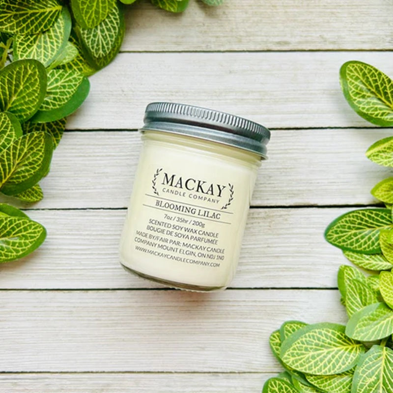 Mackay Candle Company jar on a wooden surface with green leaves