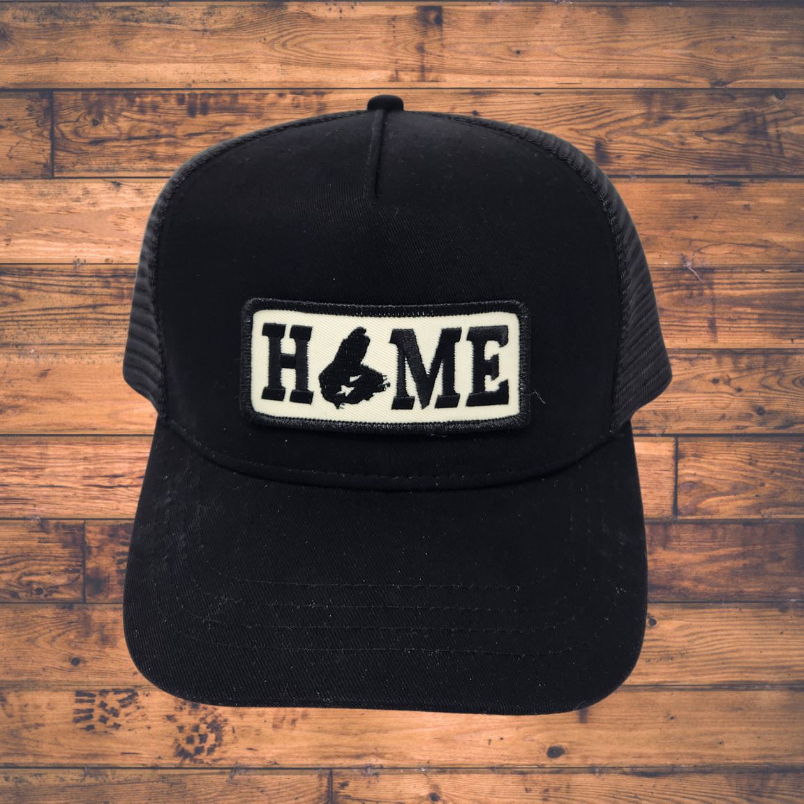Black cap with Cape Breton 'HOME' patch on a wooden surface