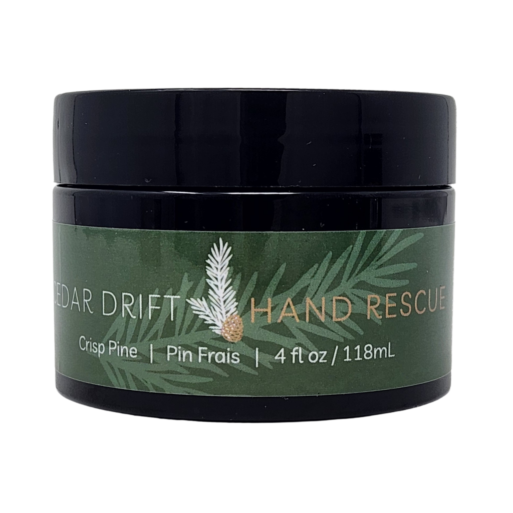 Jar of Cedar Drift Hand Rescue cream with green label and black lid on a white background