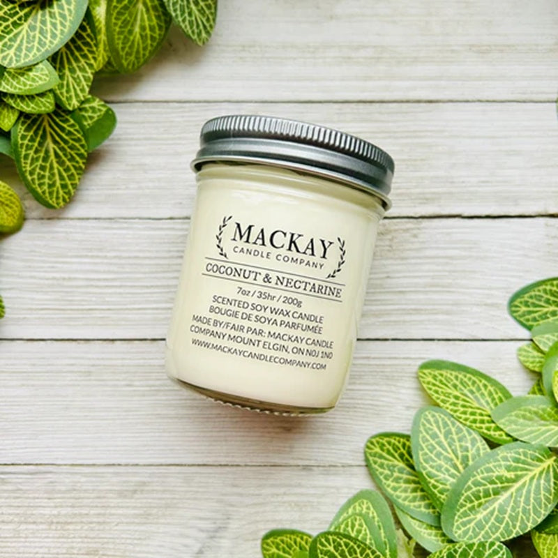 Mackay Candle Company candle jar on a wooden surface with green leaves