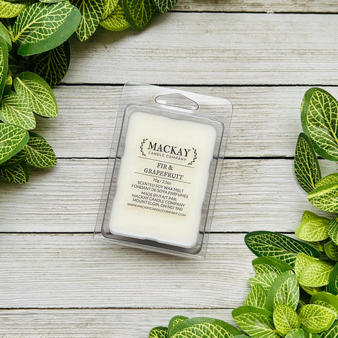 Mackay Candle Company wax melt packaging on a wooden surface with green leaves around