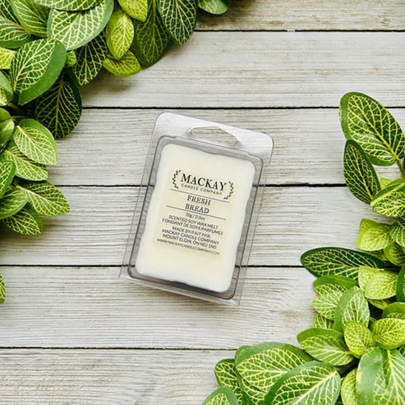 Mackay Candle Company Fresh Bread wax melt on a wooden surface with green leaves around