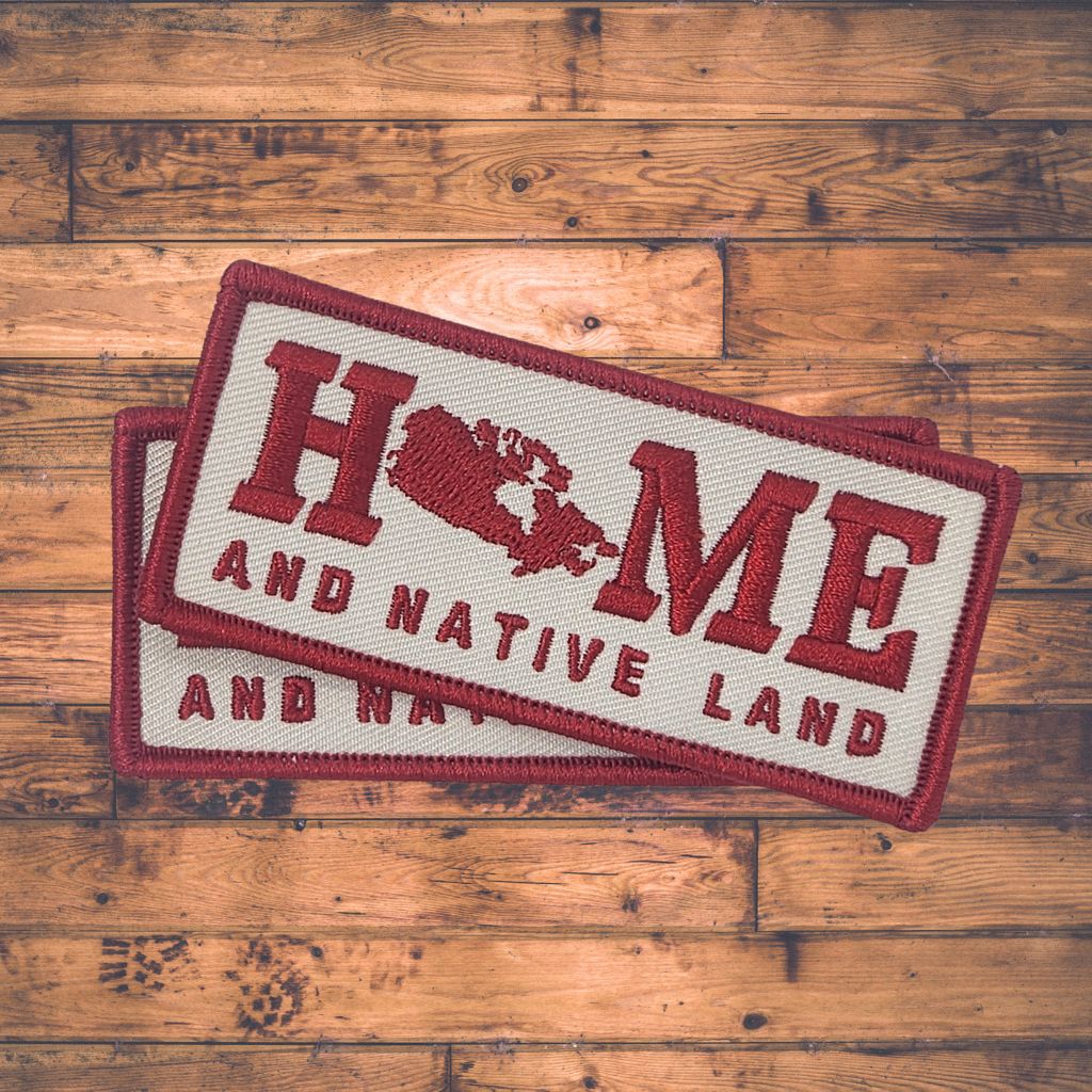 Patch with 'HOME AND NATIVE LAND' text on a wooden surface