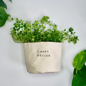 side view of a green plant inside a cloth pot cover that has dark printing on it