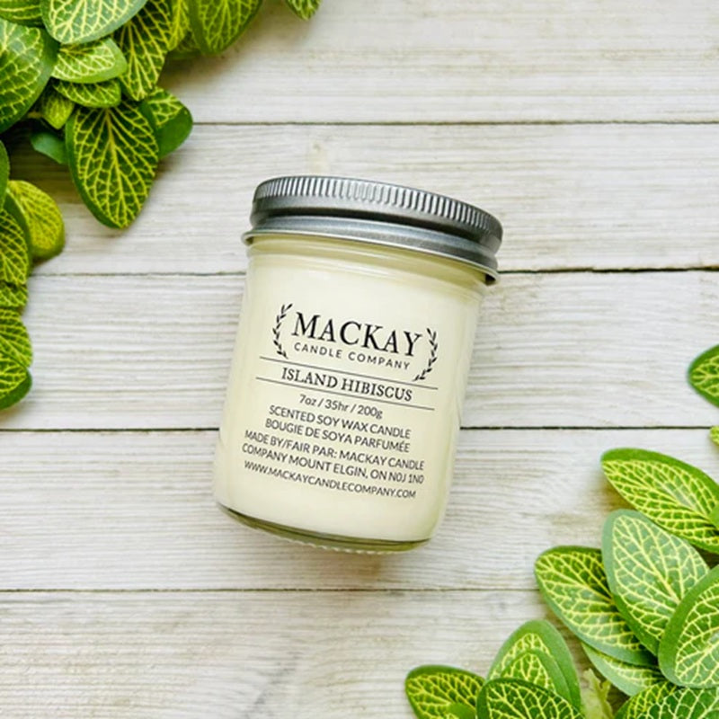 Mackay Candle Company candle jar on a wooden surface with green leaves