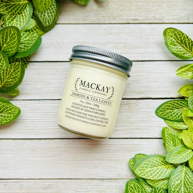 Mackay Candle Company candle jar on a wooden surface with green leaves