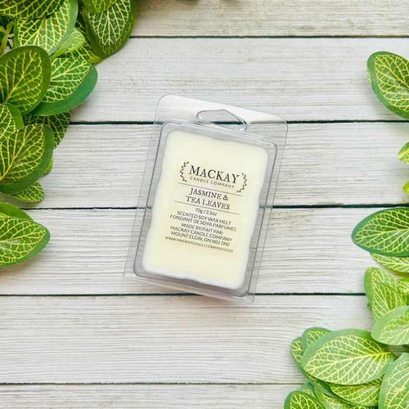 Mackay Wax Melts Jasmine & Tea Leaves packaging on a wooden surface with green leaves.