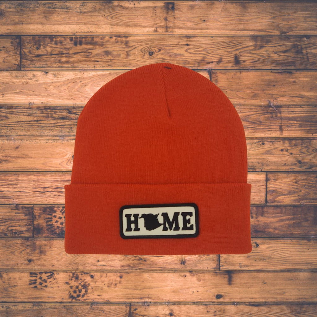 Orange beanie with a New Brunswick 'HOME' patch on a wooden surface