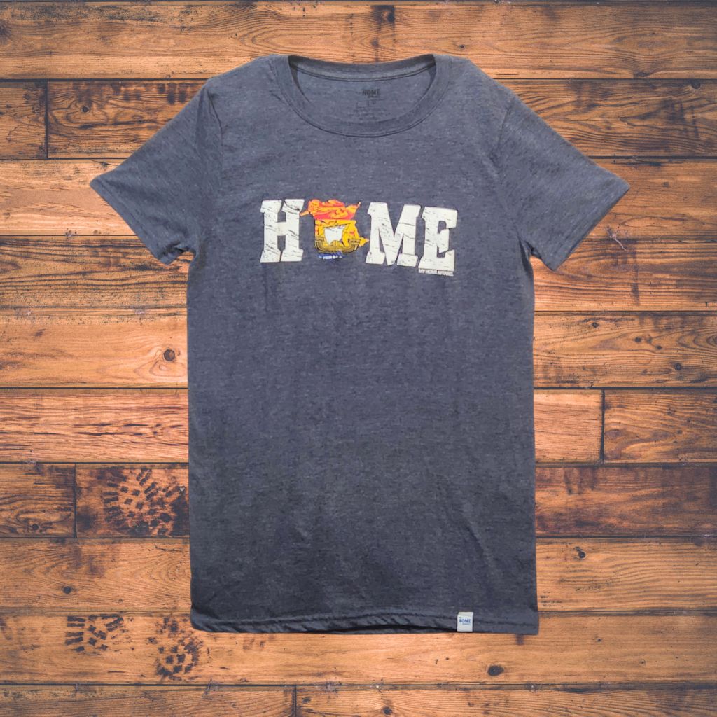 Blue t-shirt with New Brunswick 'HOME' printed on it on a wooden surface