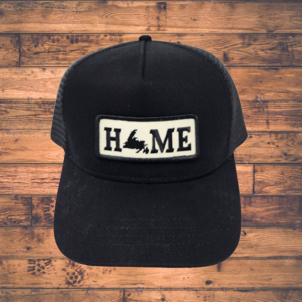 Black cap with Newfoundland 'HOME' patch on a wooden surface