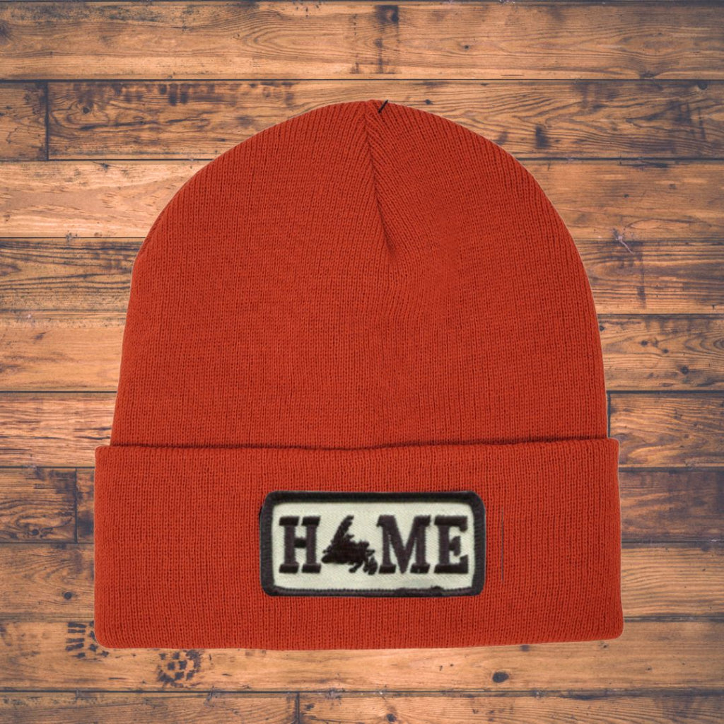 Orange beanie with a 'HOME' patch on a wooden surface