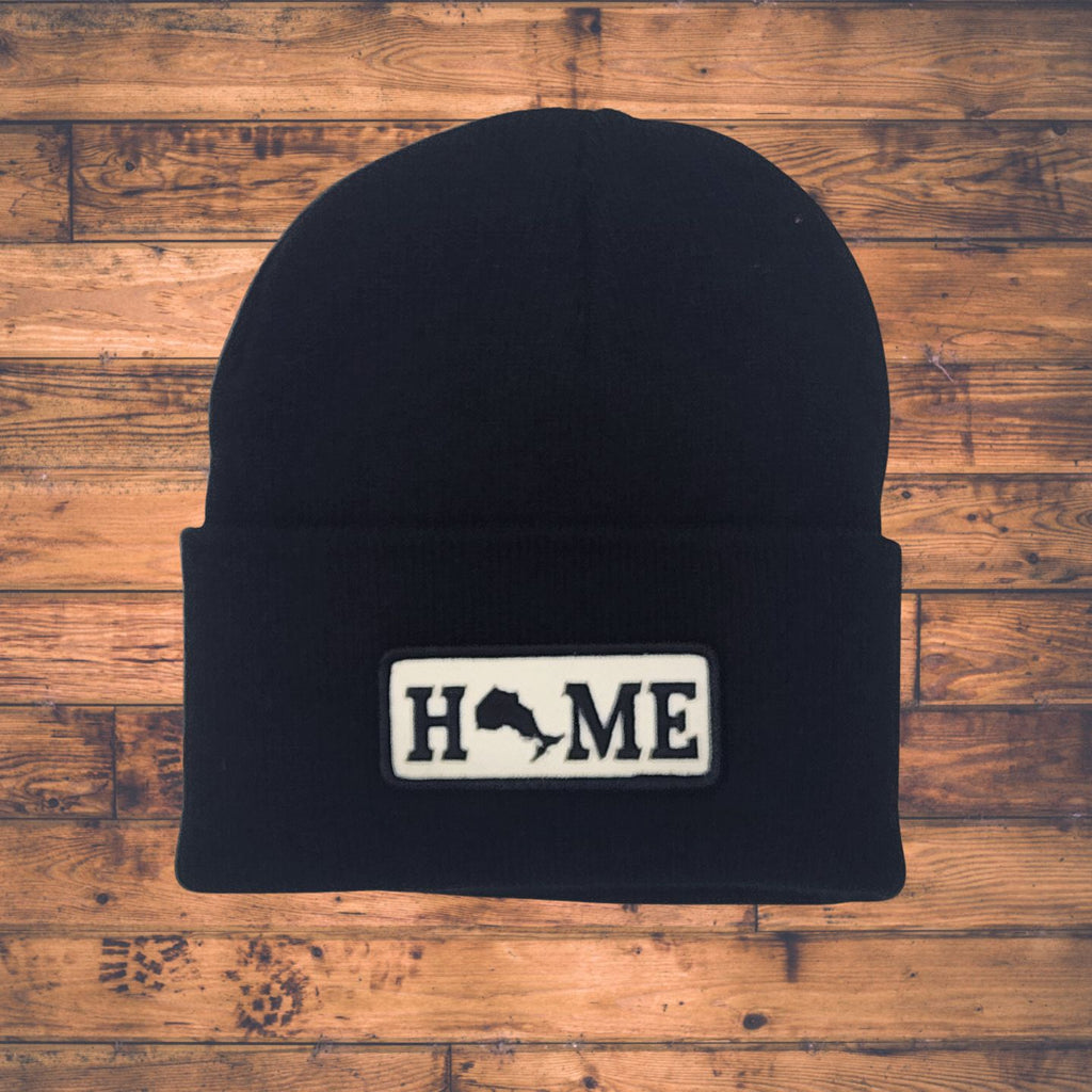 Black beanie with Ontario 'HOME' patch on a wooden surface