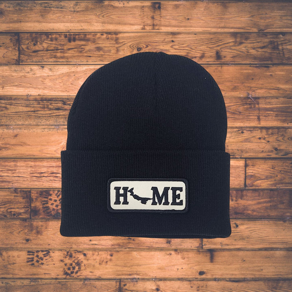 Black beanie with Prince Edward Island 'HOME' patch on a wooden surface