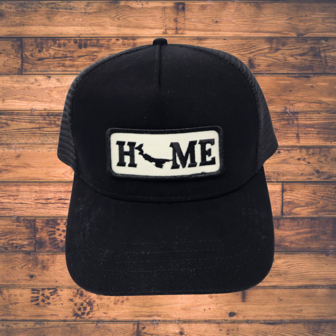Black cap with Prince Edward Island 'HOME' patch on a wooden surface