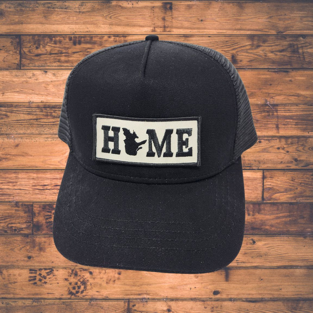 Black cap with Quebec 'HOME' patch on a wooden surface