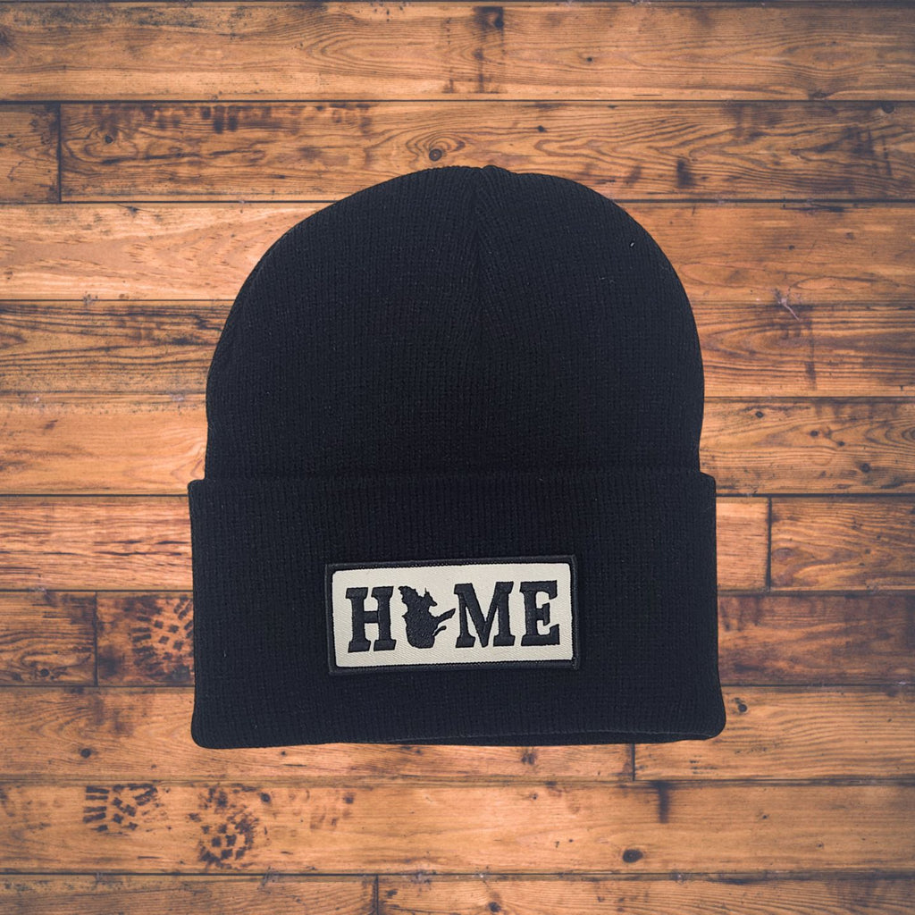 Black beanie with Quebec 'HOME' patch on a wooden surface