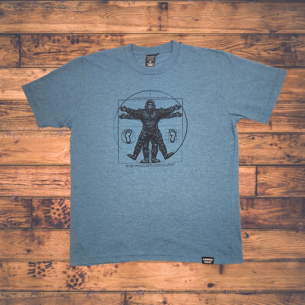blue t-shirt with Sasquatch Vitruvian design on wood panel background