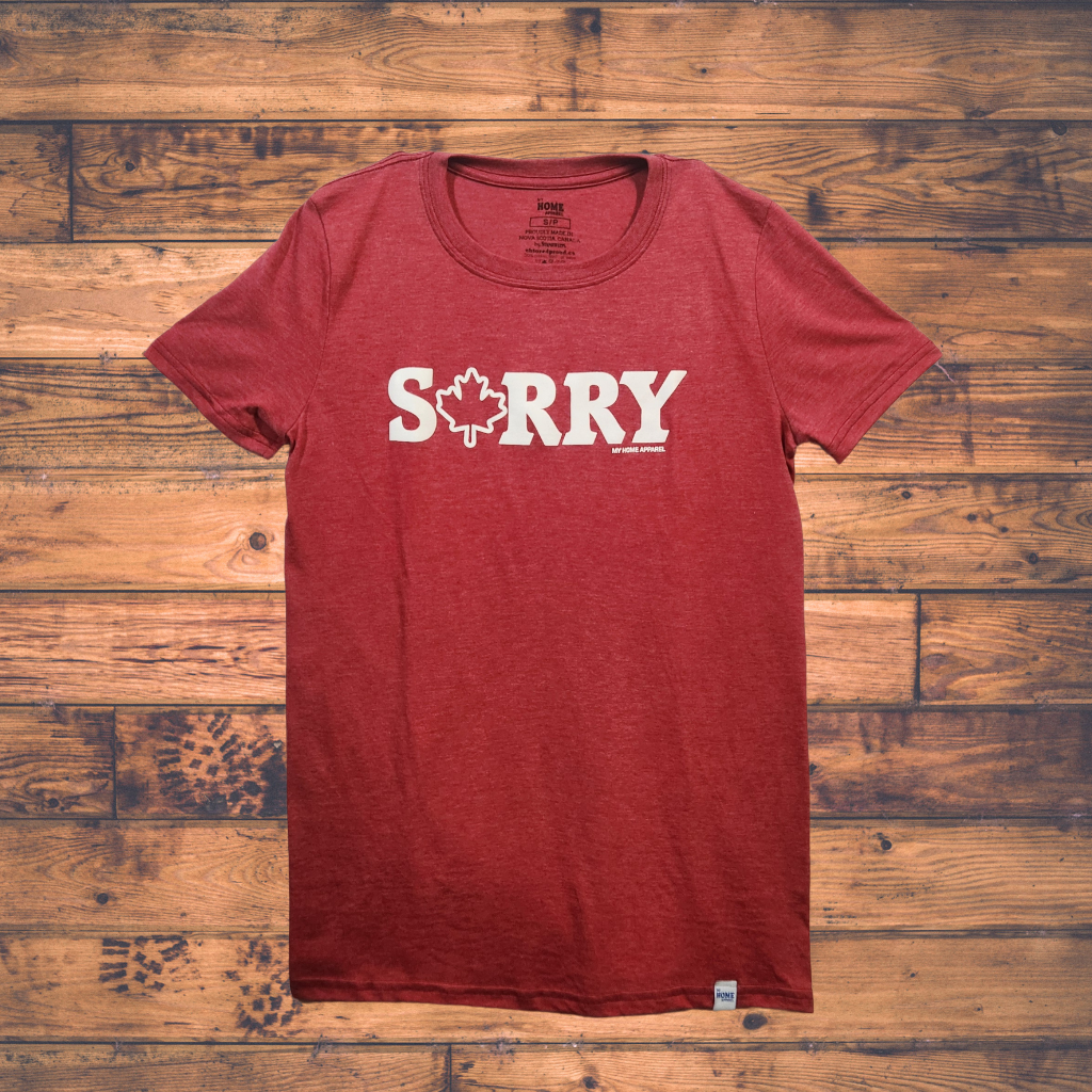 Red t-shirt with 'SORRY' printed on it against a wooden background