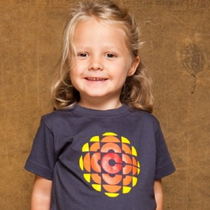 up close of a child smiling with blondish hair tied back on one side wearing a navy blue t shirt with the CBC round yellow and orange symbol
