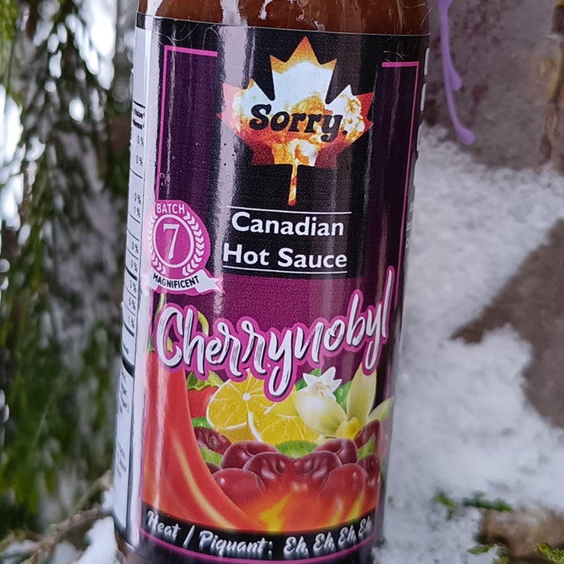 Bottle of 'Sorry! Canadian Hot Sauce' with purple sauce on a snowy background