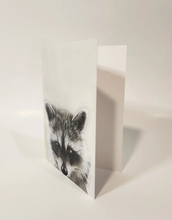 Load image into Gallery viewer, raccoon head on the bottom a card that is partially open
