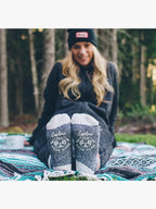 person sitting on a blanket outside with feet stretched out front showing bottoms