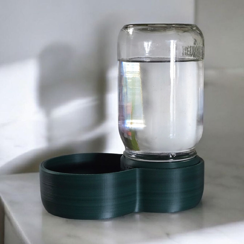 green plastic & glass pet water dispenser on a counter 