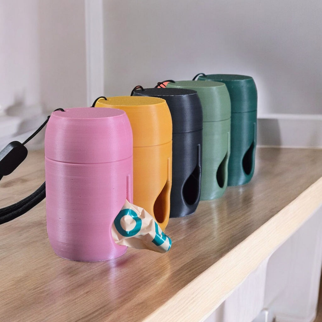 5 poop bag holders each a different colour sitting on a counter