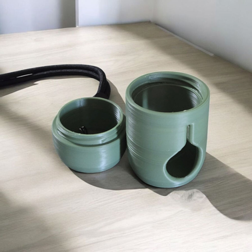 green poop bag holder sitting on a table with the lid off