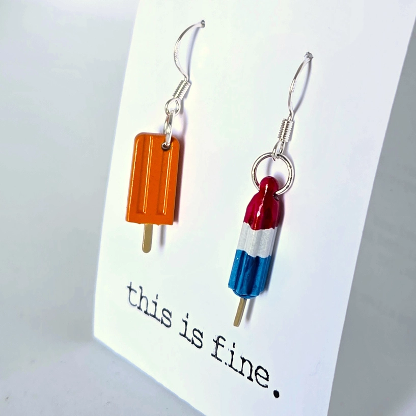 Popsicle and firecracker earrings on a card with 'this is fine.' text.