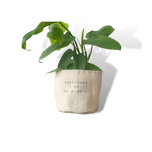 Load image into Gallery viewer, side view of a green plant inside a cloth pot cover that has dark printing on it

