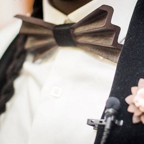 person wearing a dark brown bow tie - he is in a suite with microphone attached to lapel