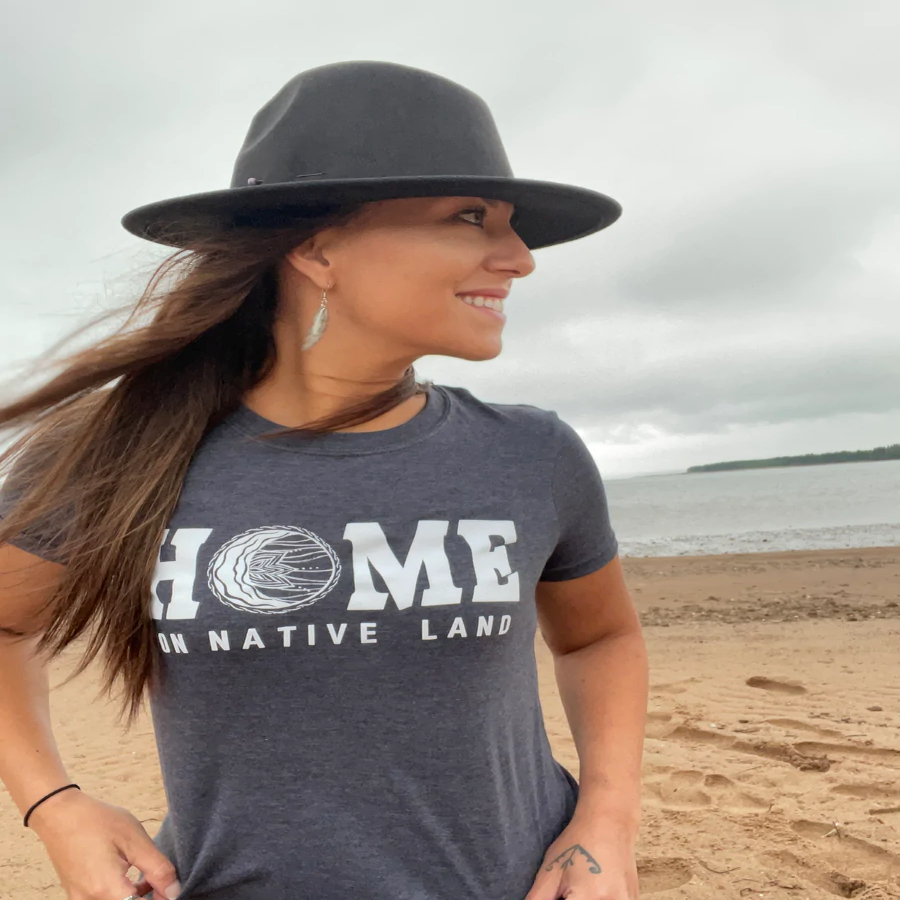 woman in brimmed hat on beach wearing the Home On Native Land T Shirt